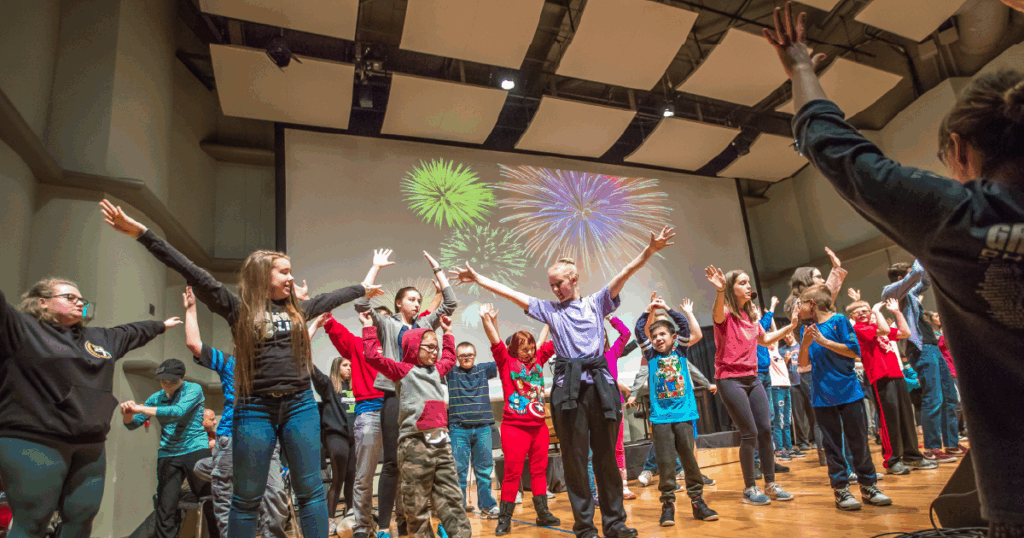Ball State students perform with children on stage in Pruis Hall.
